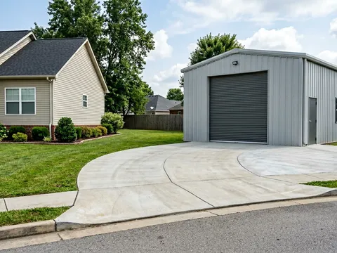 Steel garage building with all-concrete driveway and gentle curve approach