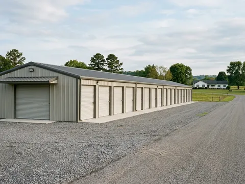 Steel storage building beside a rural road with farm landscape backdrop